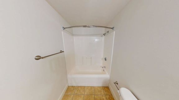 White bathtub with curved shower rod and tile floor at Bostonian Shoe Lofts Apartments, Massachusetts