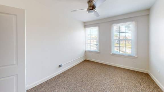 Empty bedroom with windows and tan carpet at Bostonian Shoe Lofts Apartments, Whitman, 02382