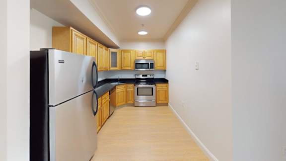Compact kitchen with stainless appliances and wood cabinets at Bostonian Shoe Lofts Apartments, Massachusetts