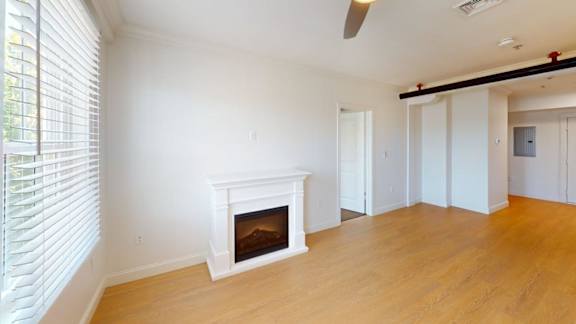 Living room with white fireplace and hardwood floors at Bostonian Shoe Lofts Apartments, Whitman, MA 02382