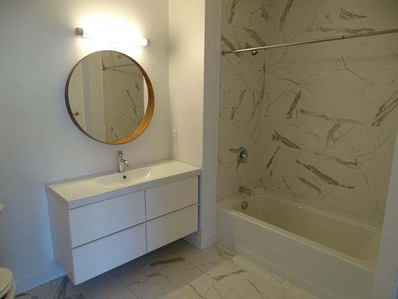 A bathroom with a marble wall and a white sink.