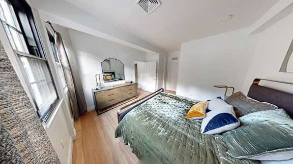 A bedroom with a bed, dresser, and mirror.