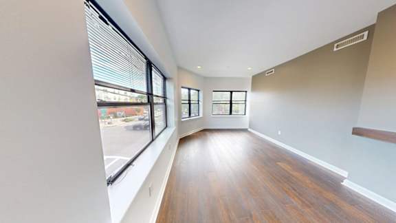 Bright living room with hardwood floors and large windows at Ten Front Apartments, Massachusetts