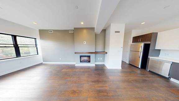 Open concept living space with fireplace and modern kitchen at Ten Front Apartments, Weymouth, MA