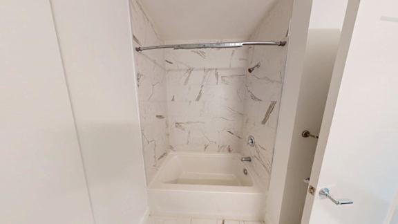 Bathtub and shower with marble surround at Ten Front Apartments, Weymouth, MA 02189