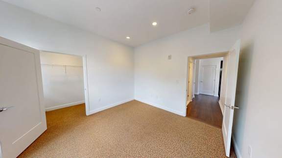 Empty bedroom with carpeting and walk-in closet at Ten Front Apartments, Weymouth