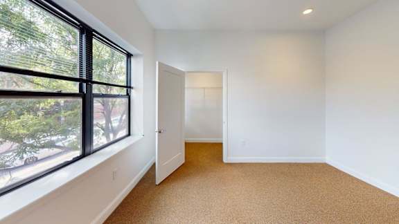 Bright bedroom with large window and closet access at Ten Front Apartments, Weymouth