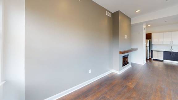 Open living room with hardwood floors and builtin fireplace at Ten Front Apartments, Weymouth, MA