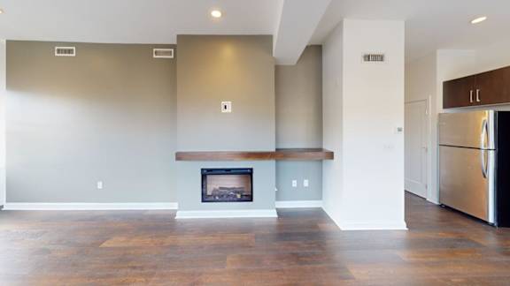 Contemporary living room with fireplace and wooden mantel at Ten Front Apartments, Weymouth, 02189