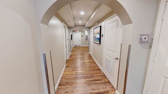 Hallway with arched entry and wood style flooring at Bostonian Shoe Lofts Apartments, Whitman