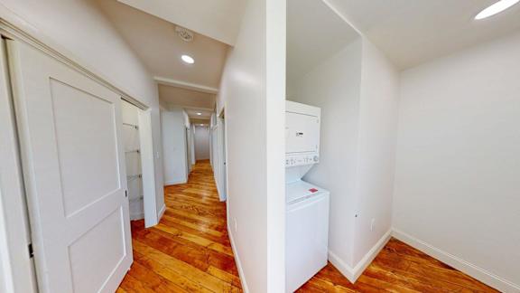 A hallway with a washing machine in the corner.