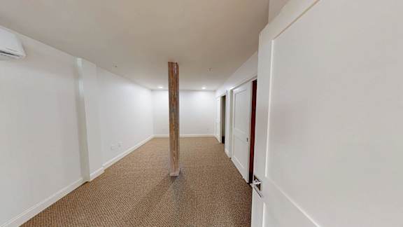 A long hallway with a carpeted floor and white walls.