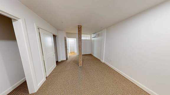 A long hallway with white walls and carpeted floor.