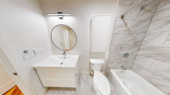 A white bathroom with a marble tile shower.