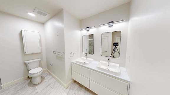 A white bathroom with a toilet, sink, and mirror.