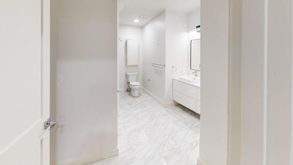 A white bathroom with a toilet, sink, and mirror.