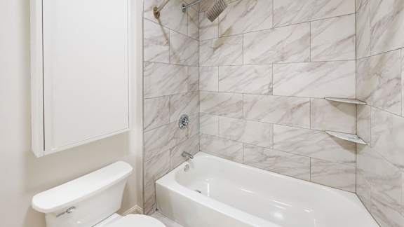 A white bathroom with a tub and toilet.