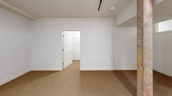 A room with a carpeted floor and a wooden pillar.