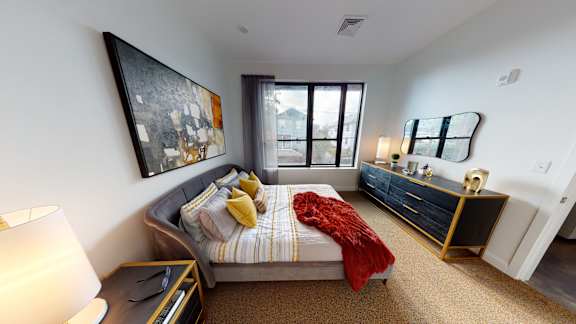 A bedroom with a bed, a nightstand, and a painting on the wall.