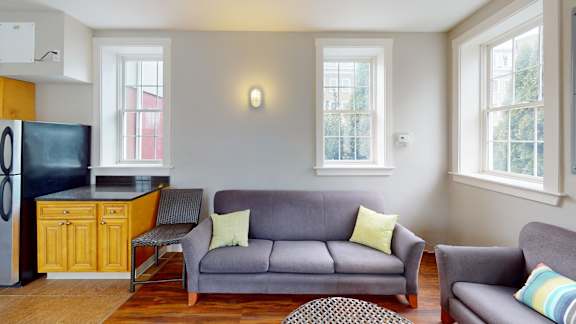 A grey couch with yellow pillows sits in a living room.