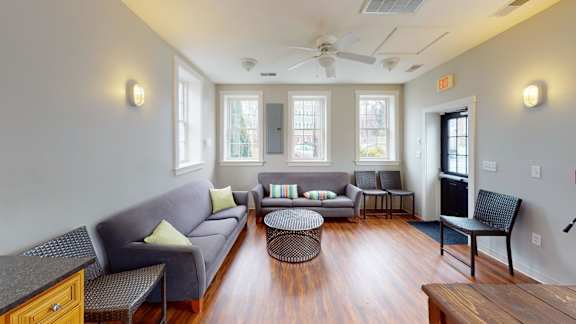 A living room with a grey couch, a black chair, and a wooden table.
