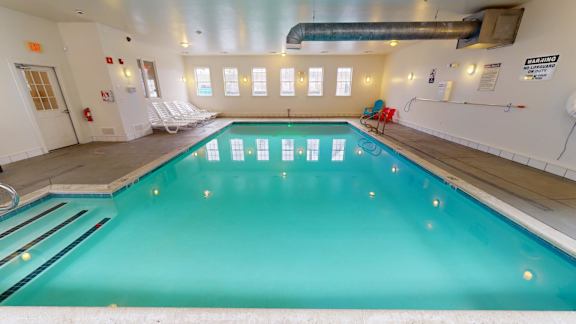 Indoor swimming pool with lounge chairs and windows at Bostonian Shoe Lofts Apartments, Whitman, MA 02382