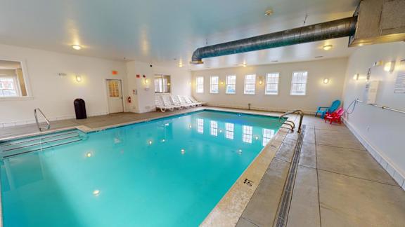 Indoor swimming pool with lounge chairs and natural light at Bostonian Shoe Lofts Apartments, Whitman, MA