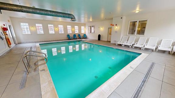 Indoor pool with lounge chairs and natural lighting at Bostonian Shoe Lofts Apartments, Whitman, 02382