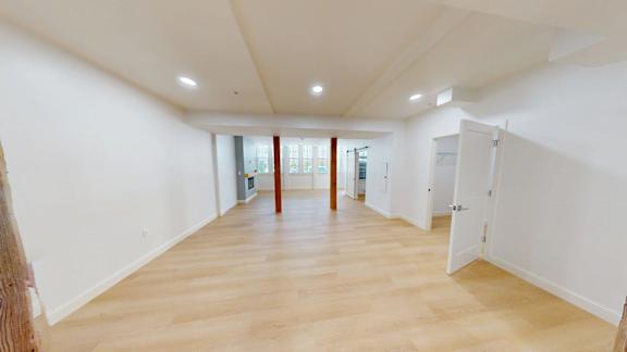 A large empty room with wooden floors and white walls.