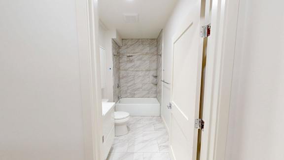 A white bathroom with a marble tiled shower.
