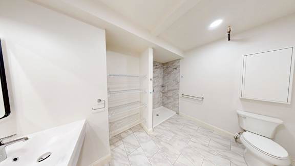 A white bathroom with a toilet, sink, and shower.