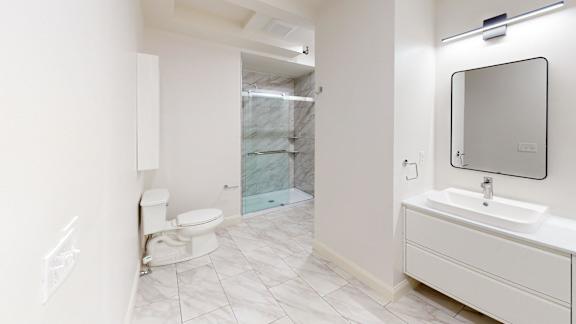 A bathroom with a toilet, sink, and mirror.
