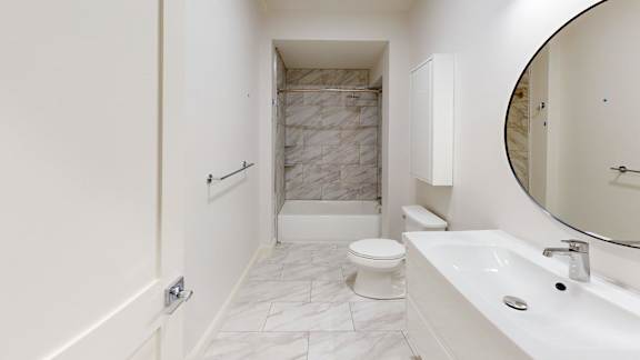 A white bathroom with a marble tile shower.