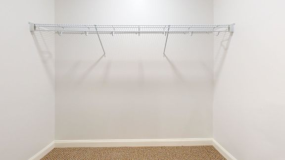 Empty white closet with a metal rack.