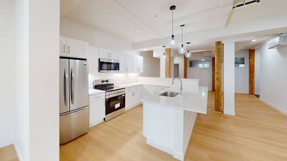 A modern kitchen with wooden floors and stainless steel appliances.