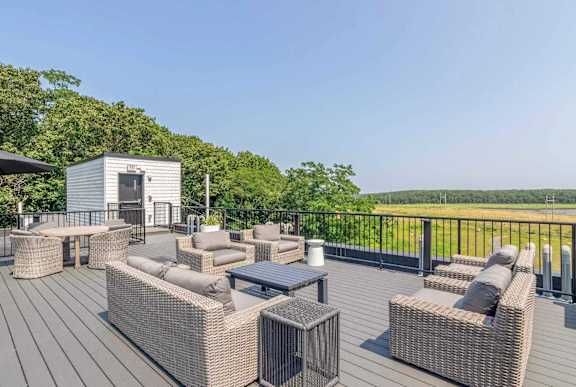 A wooden deck with wicker furniture and a small building.