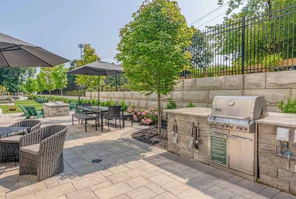 A patio with a grill and chairs.