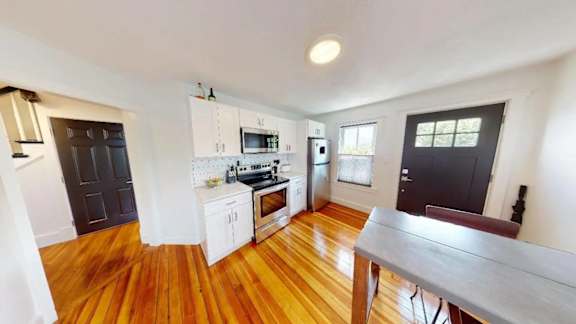 A kitchen with wooden floors and white walls.