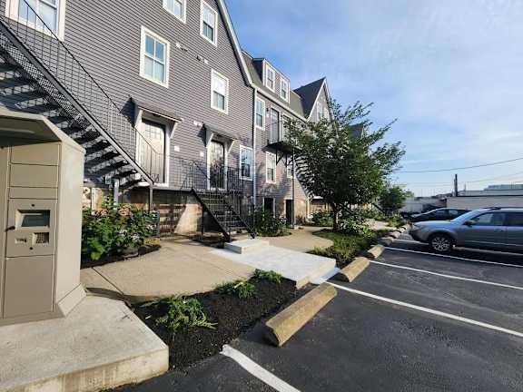 A parking lot in front of a building with a car parked.