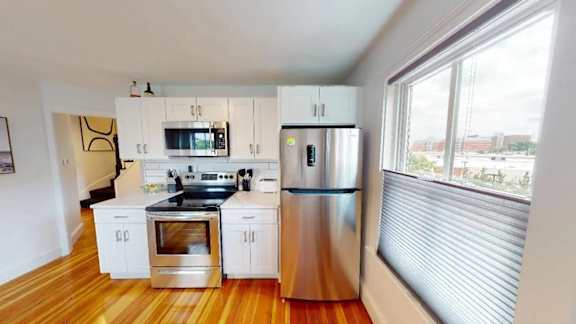 A modern kitchen with stainless steel appliances and wooden floors.