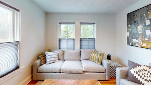 A living room with a couch, pillows, and a painting on the wall.