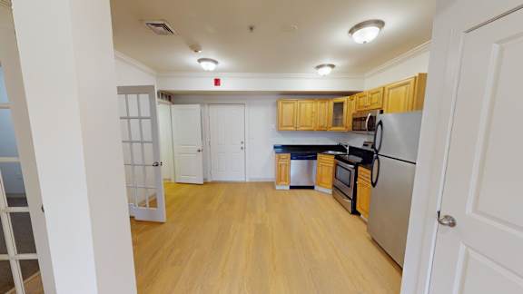 Open kitchen with hardwood floors and stainless appliances at Bostonian Shoe Lofts Apartments, Whitman, MA