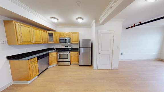 Open kitchen with wood cabinets and black countertops at Bostonian Shoe Lofts Apartments, Whitman, 02382