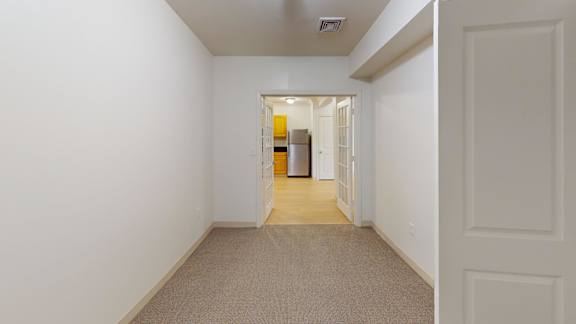 Empty carpeted room with hallway view to kitchen at Bostonian Shoe Lofts Apartments, Whitman, MA