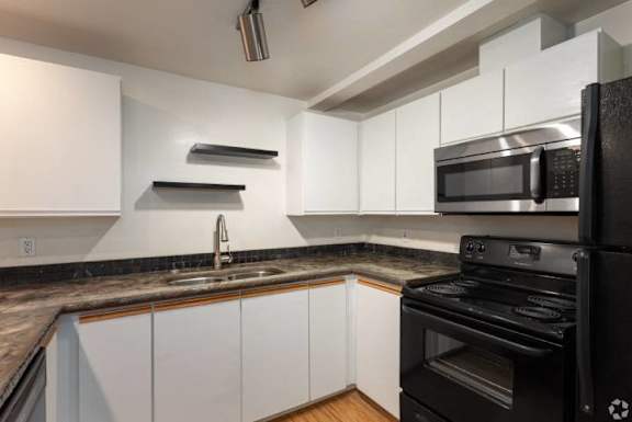 A modern kitchen with black appliances and white cabinets.