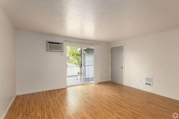 A room with wooden floors and white walls, featuring a sliding glass door.
