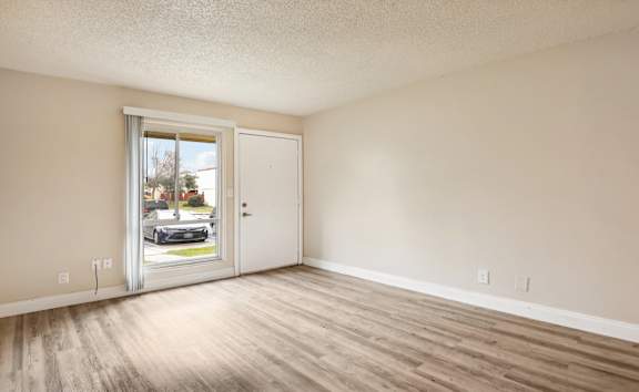 A room with a white door and a window with a view of a street.
