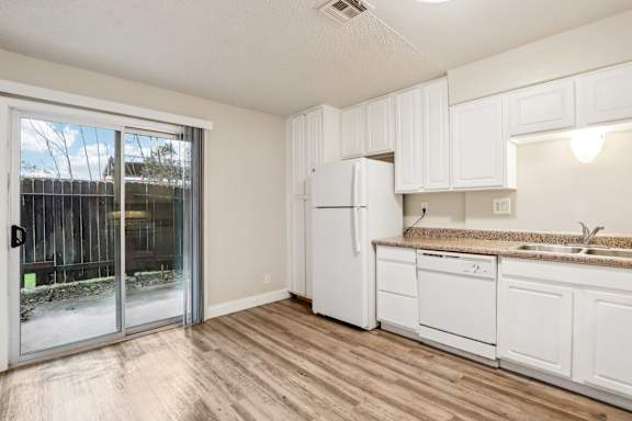 A kitchen with white cabinets and a white fridge.