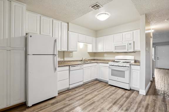A kitchen with white appliances and cabinets.
