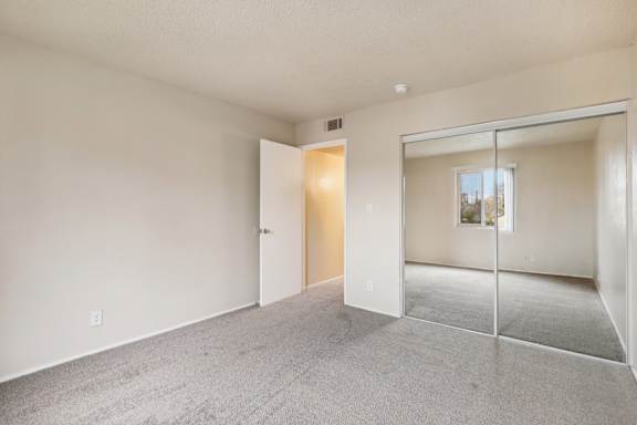 A room with a carpeted floor and a sliding glass door leading to a balcony.